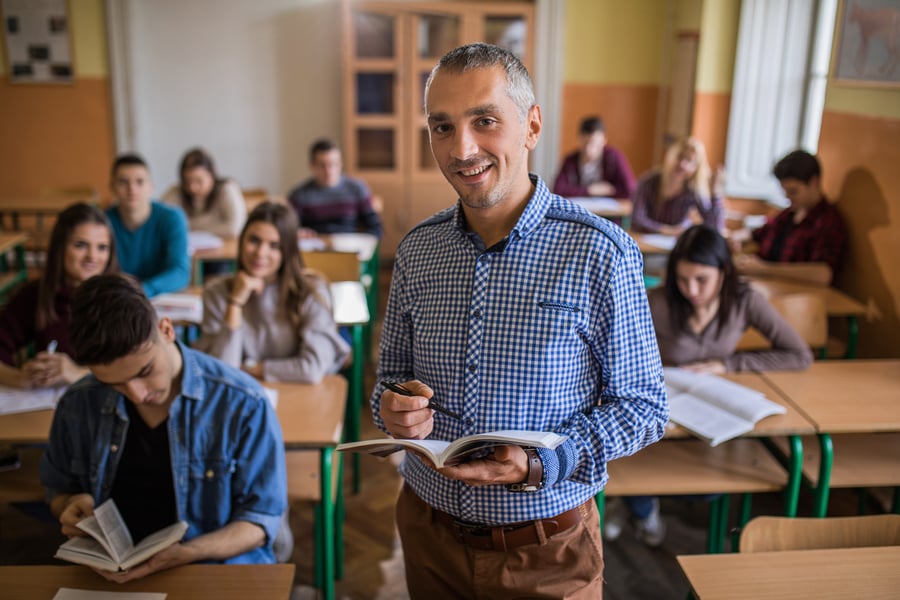 Happy-high-school-teacher-looking-at-camera-during-the-class-in-the-classroom.-859610548_6720x4480 (1)