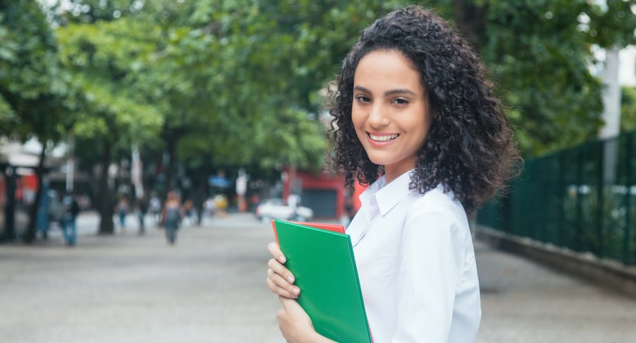 Happy-latin-female-student-with-curly-hair-and-white-shirt-845460816_7570x5475