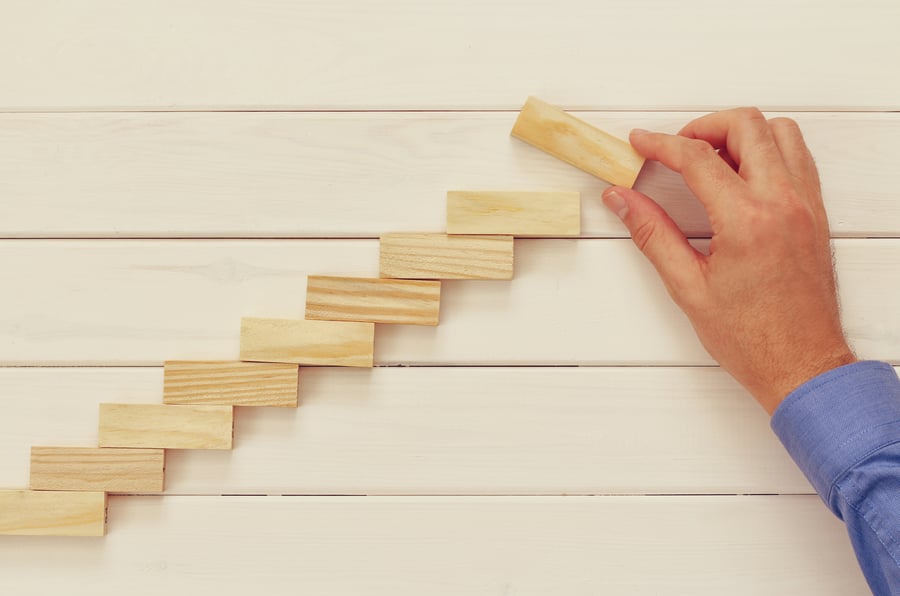 Male-hand-building-ladder-from-domino-bricks-589971408_4779x3168 (1)